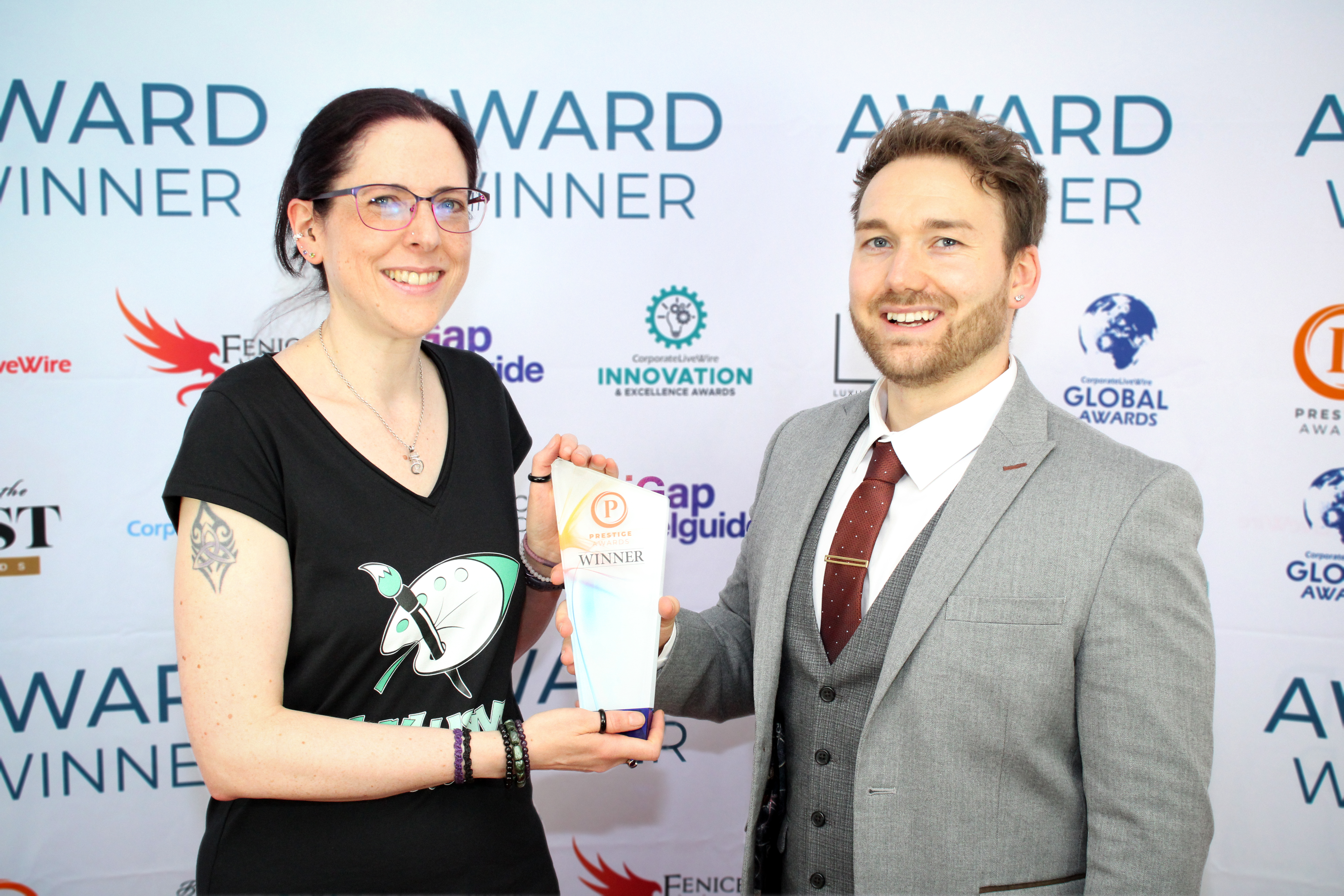 Vicky is receiving her award from Prestige Awards staff in front of an Award Winner banner