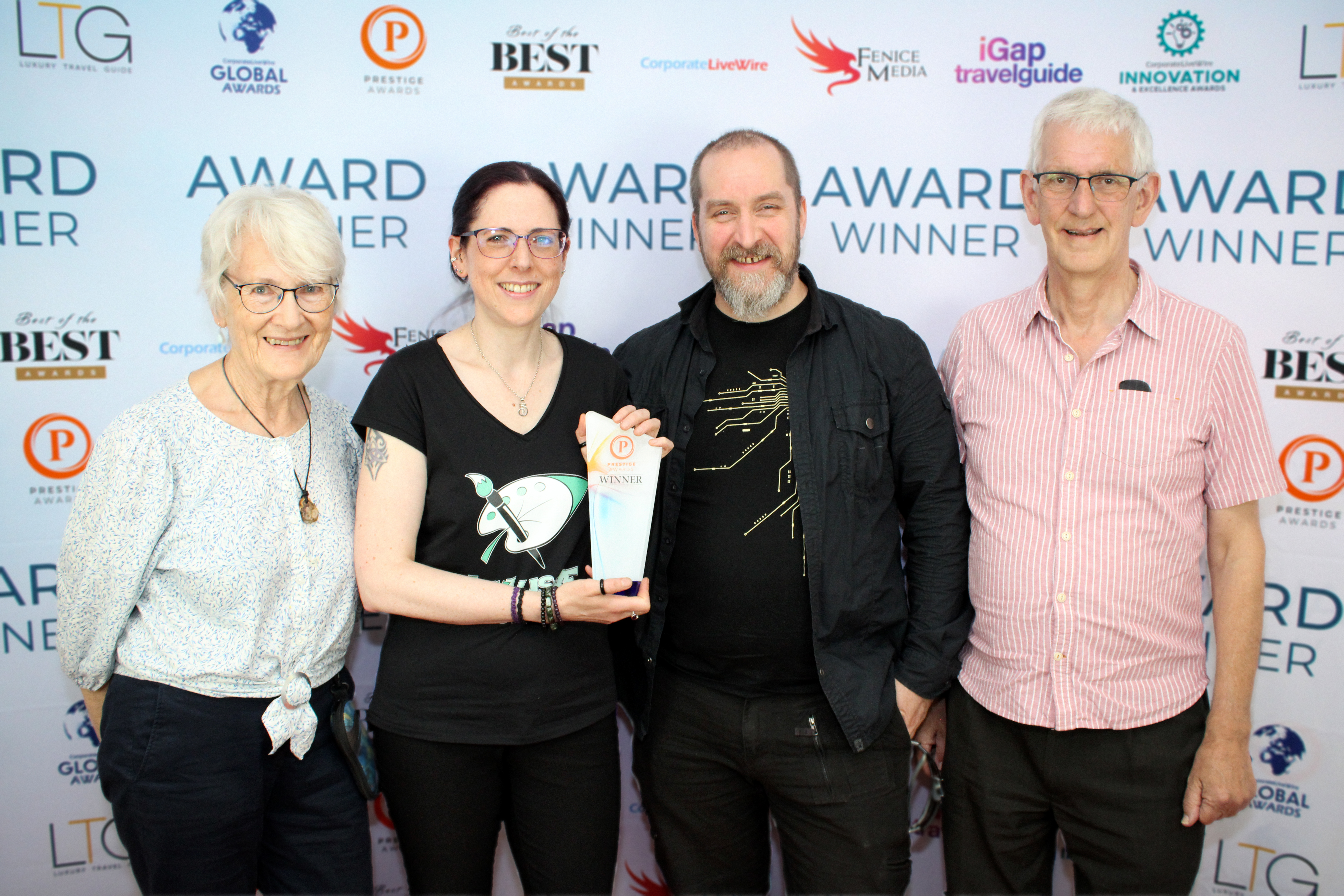Four people stand in front of an Award Winner Banner. From left to right, Rosemary Clarke, Vicky Bowskill (holding an award), John McGrath and Michael Stroud.